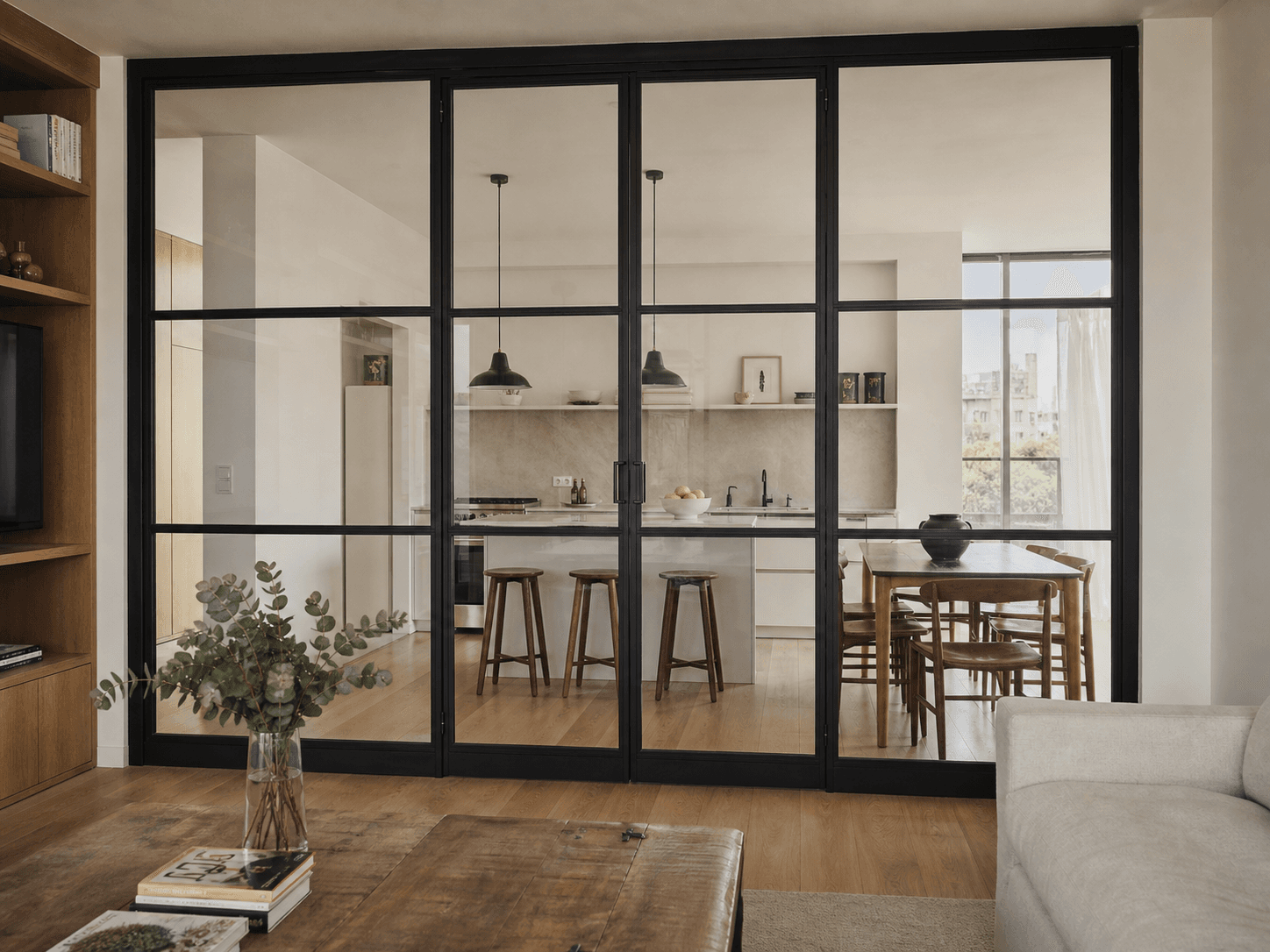 Puerta corrediza de hierro negro y vidrio que separa un escritorio del living